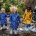 children jumping in a puddle with rain coats on