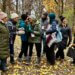 A group of teachers, outdoors in the woods on a fall day, participate in nature-based education training