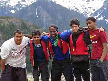 Youth locking arms outside in front of a mountain.