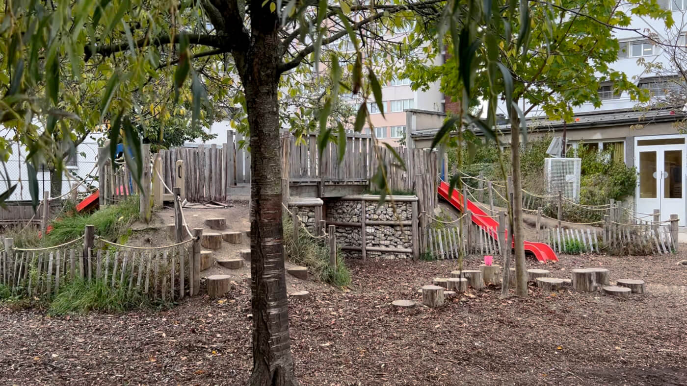 A natural play space utilizing stumps, rocks, wooden structures and a slide.