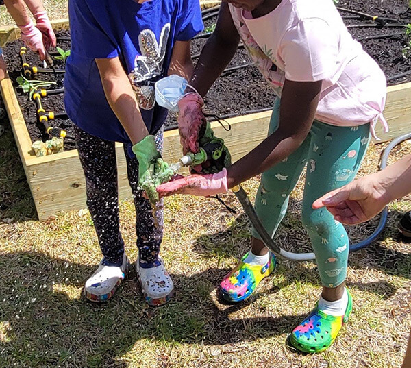 Children rinse off their gloves after planting at Union Missionary Baptist Preschool. Photo courtesy of Smart Start of New Hanover County.
