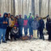 A group of young people stand around a circle in a snow-covered forest cheering for each other.