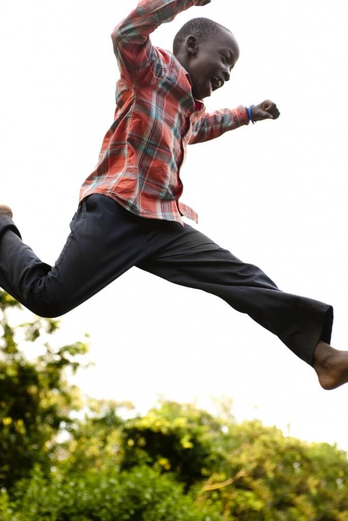 Boy leaping across fields.