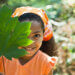 Young girl outdoors smiling with leaf.