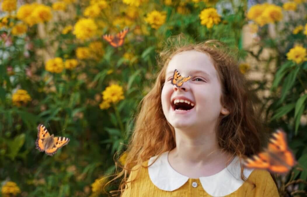 child with butterfly on their nose and more butterflies flying around